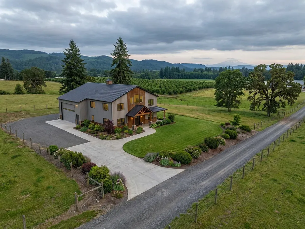 A completed barndominium home viewed from the front corner, with finished landscaping, a covered entry porch and an attached shop bay.