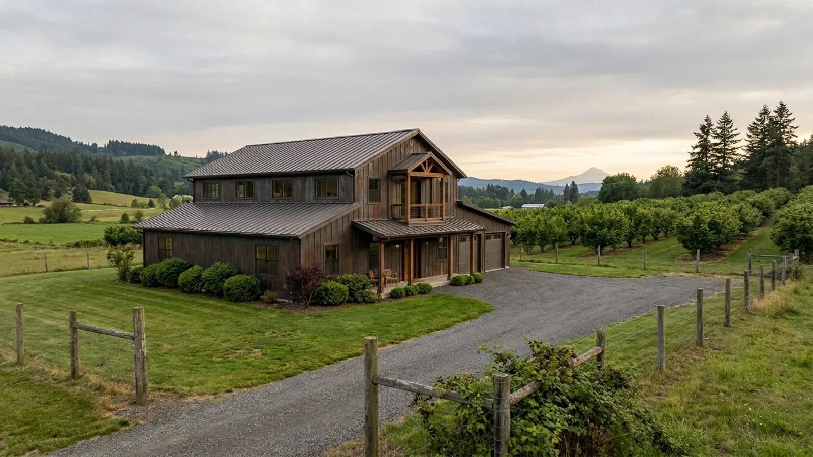 A completed two-story barndominium with visible second-story windows and a small covered balcony above the entry porch.